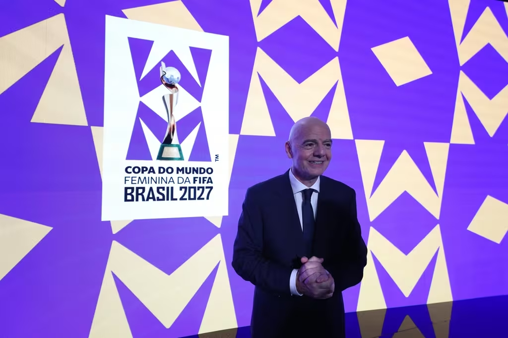 Gianni Infantino, presidente da Fifa, ao lado da marca oficial do evento