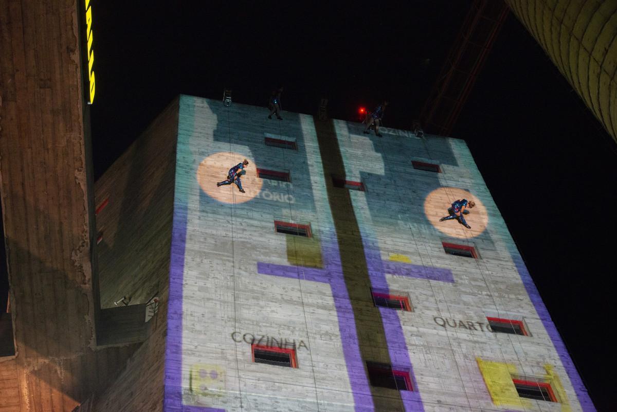 Artistas da Cia VEDA desafiam a gravidade em Correnteza, espetáculo que transforma a fachada do ShoppingSantaÚrsula em palco para dança vertical e projeções visuais