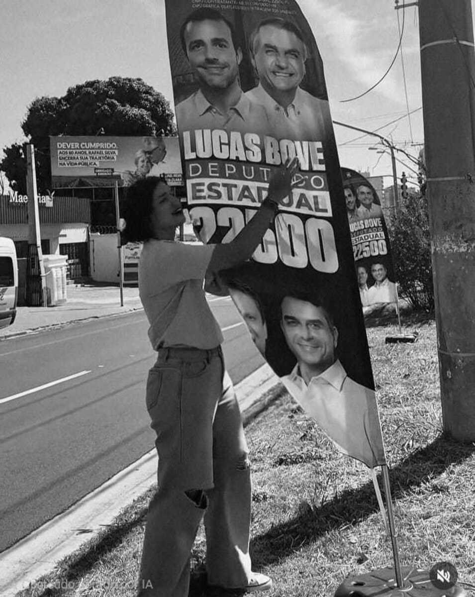 Vereadora Duda Hidalgo ao lado de um banner de Lucas Bove (PL)