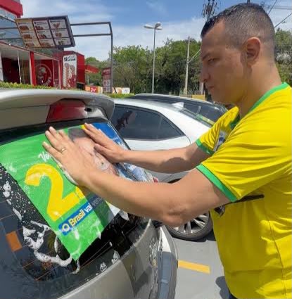Apoiador cola adesivo do candidato a presidente Flávio Bolsonaro em vidro de veículo